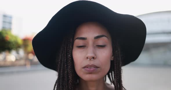 Bohemian mixed race girl looking serious on camera with city in the background