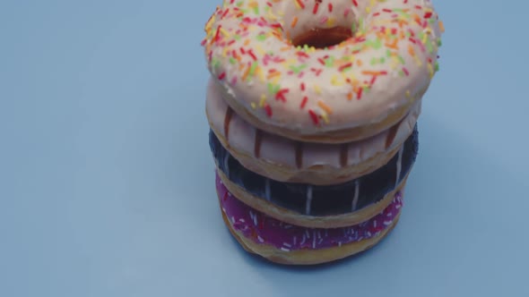 Huge Fresh Donuts with Colored Glaze and Multicolored Sprinkles Lie on Top of Each Other Closeup