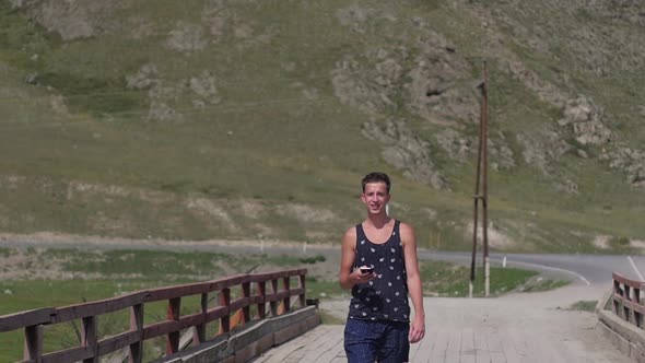 Young Handsome Man Walking in the Mountains. A Man Talking on the Phone Against the Backdrop of the