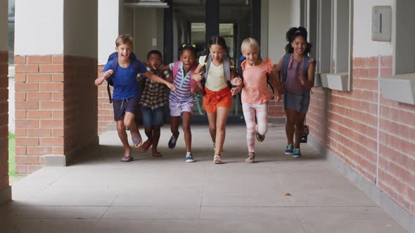 Video of happy diverse pupils running on school corridor