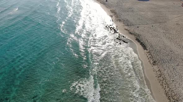 Drone Moves Along Sandy Beach and Turquoise Waves of Mediterranean Sea on Sunset