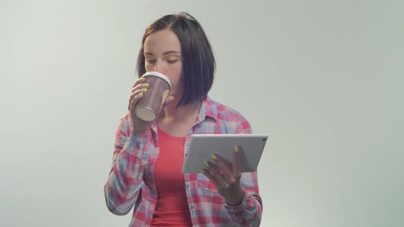 Woman reading on a tablet and drinking coffee 