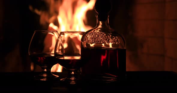 Two Glasses of Cognac and a Bottle Near the Fireplace