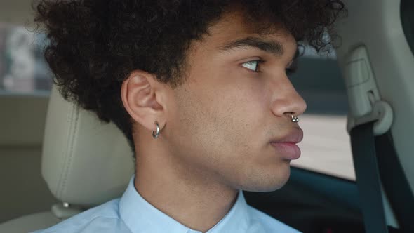 Close Up Young African American Guy in Shirt Sitting in Modern Car Interior Looking at Camera