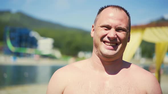 Close-up, Portrait: Man on Beach, Bare-chested, Laughs. There Are Drops of Water on His Body. Short