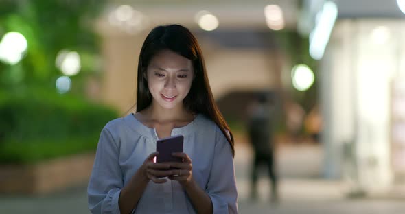 Woman use of mobile phone in the city at night
