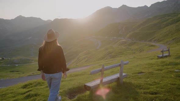 Travel  woman in hat in lights of a sun walks and sits on bench against mountain landscape