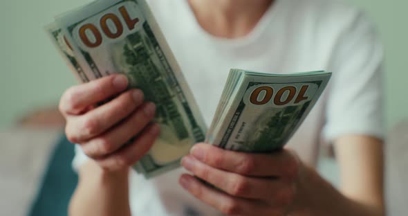 Closeup of a Young Woman Counting Hundreddollar Bills at Home