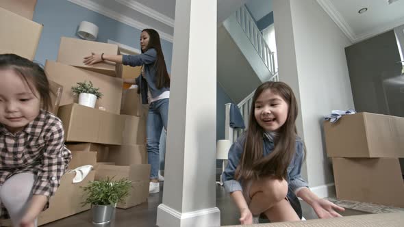 Happy Mother and Kids Unrolling Carpet in New House