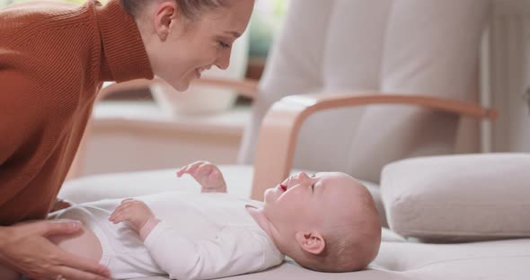 Close Up of the Baby Lying on Its Back on the Couch Smiling and Happy Looking at Its Mother Who