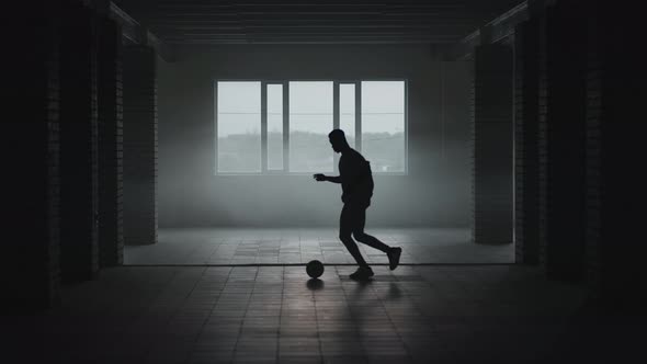 The Silhouette of a Football Player Training in an Underground Parking Lot in the Sun and Rising