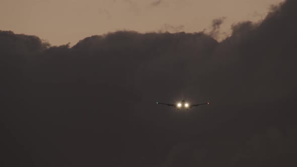 Plane with Headlights Ascending Against Heavy Clouds in Evening Sky