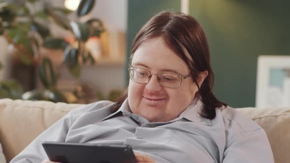 Cheerful Man with Down Syndrome Using Tablet