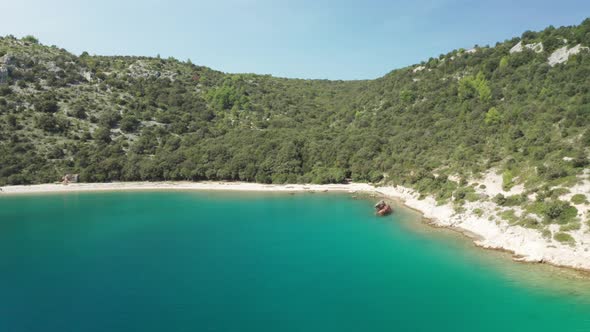 Cinematic panorama shot of small beach with a ship wreck on the right side of the frame. Camera trac