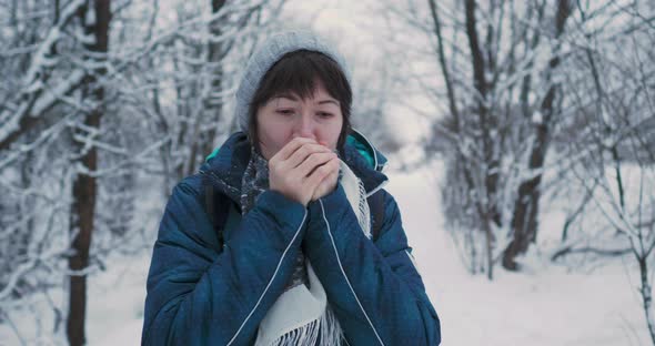 Woman Warms Her Cold Hands with Breath Fun in Snowy Winter Forest