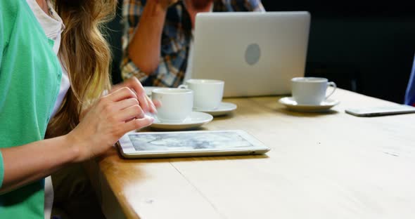 Woman using digital tablet while having coffee