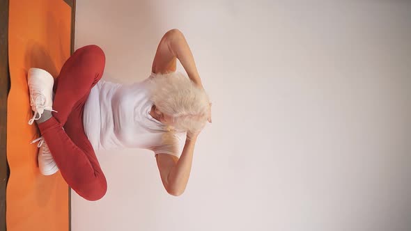 Grayhaired Elderly Woman Does Sports at Home Does Exercises for Body Flexibility Takes Care of Her