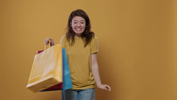 Smiling Woman Holding Shopping Bags Feeling Ecstatic and Pleased with Purchase Doing Thumb Up Hand
