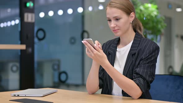 Serious Businesswoman Using Smartphone at Work