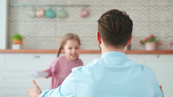 Cute little girl hugging daddy in living room. Young family on Father's Day holiday