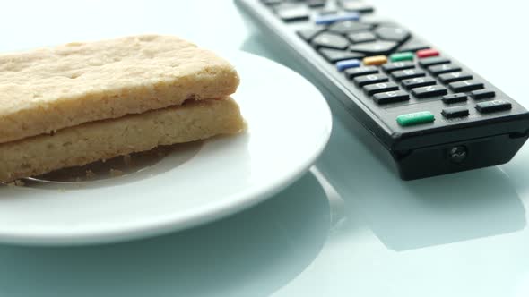 Cookies and Tv Remote on Color Background