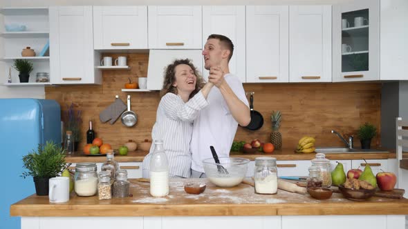 Young Couple In Love Dancing In Kitchen At Home While Cooking Breakfast