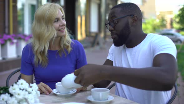 Multiracial Woman and Man Drinking Tea and Talking in Outdoor Restaurant