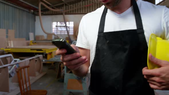 Attractive carpenter using his phone and smiling for camera