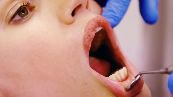 Dentist examining a female patient with tools