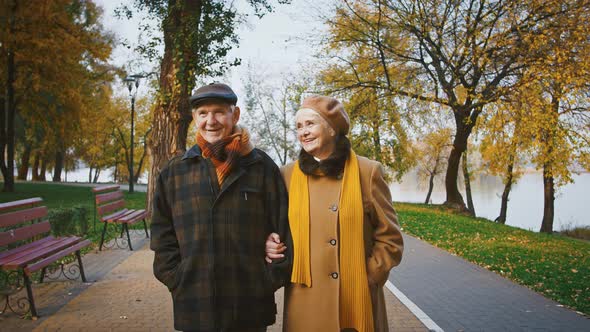 Happy Spouses Grandparents in Elegant Outerwear are Talking and Smiling During a Walk in Autumn Park