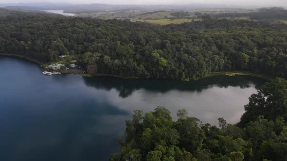 Aerial drone video revealing a large volcanic crater lake fringed with a lush tropical rainforest