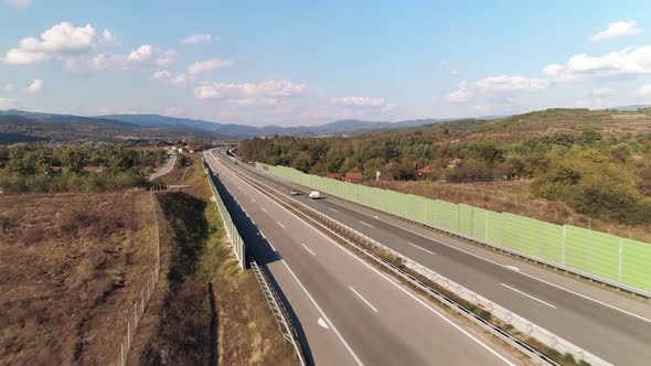 Straight motorway highway. Cars passing. Sound barriers.