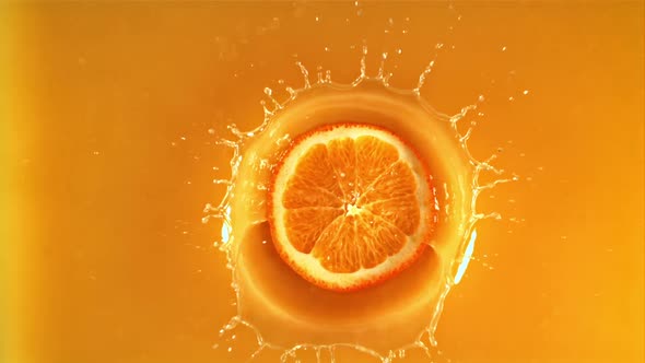 A Round Piece of Fresh Orange Falls Into Orange Juice with Splashes