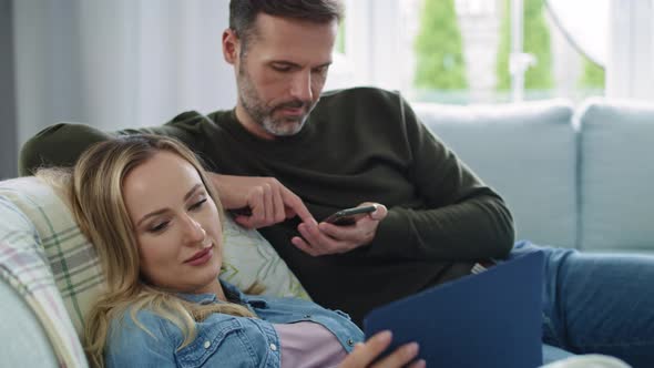 Bored couple using technology in living room