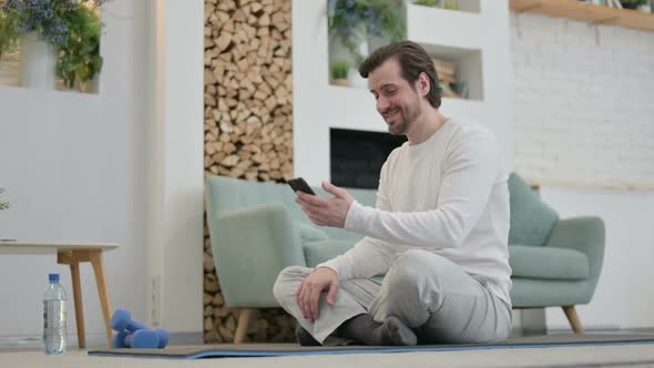 Young Man Talking on Video Call on Laptop While on Yoga Mat