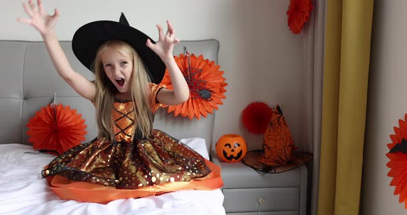 Cute Caucasian Little Girl with Blonde Hair Seven Years Old in Witch Dress and Hat Having Fun and