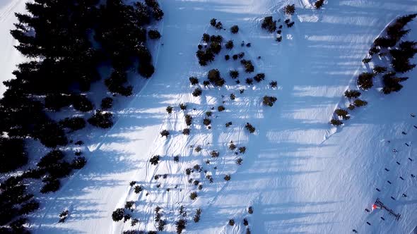 Aerial view of the ski lift at the foot of the ski slope with a crowd of skiers and snowboarders. Al