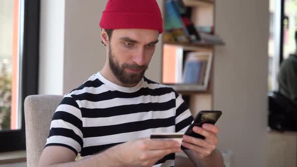 Smiling, positive guy with a beard is shopping online.