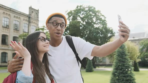 Young Beautiful International Couple is Making a Selfie in Front of the University Building Smiling