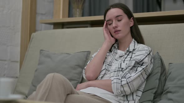 Tired Young Woman Sitting on Sofa and Taking Nap