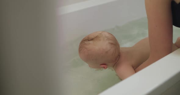 Cute Blueeyed Infant Lying in a Bath on Mother's Hands and Cognizing Arounds