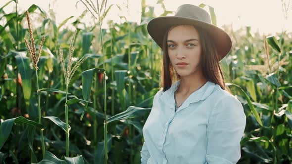 Portrait of Young Farmer Girl in Hat Shows Up with Hand Her Corn Field at Organic Farm. Girl Smiling