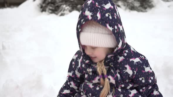 A Cheerful Child Plays and Throws Snowballs Outdoors