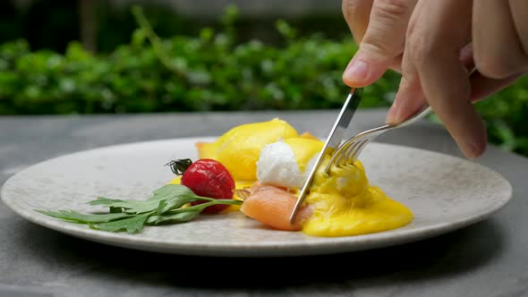 Male Hands Cut Eggs Benedict and Eat Man Has Breakfast Lunch or Dinner in Cafe