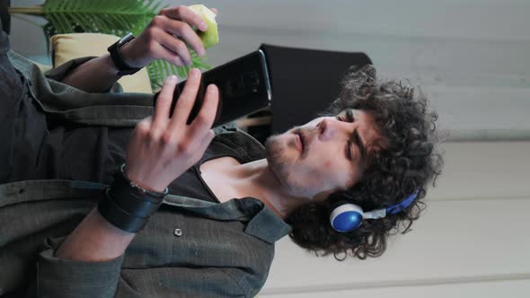 Young Man Listening to the Music and Gesturing While Eatting an Apple Vertical Video