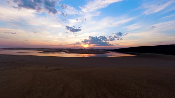 Time lapse of sunset reflection over river mouth and sand dunes, Africa