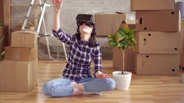Portrait of a Young Woman in Virtual Reality Glasses Sitting on the Floor Next To the Boxes