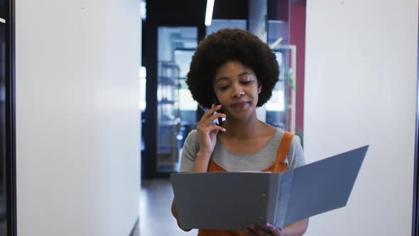 Mixed race businesswoman walking going through paperwork in modern office