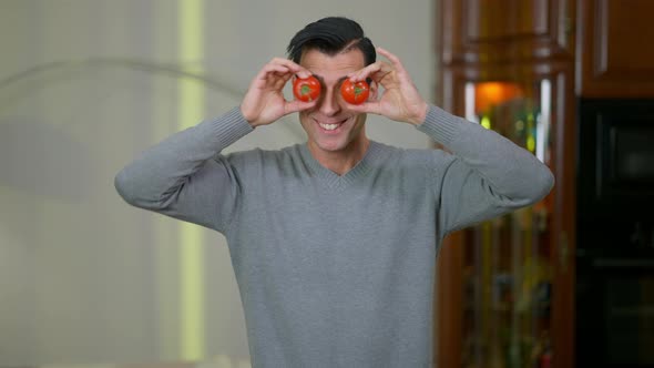 Portrait of Joyful Middle Eastern Man with Toothy Smile Holding Tomatos in Hands Over Eyes