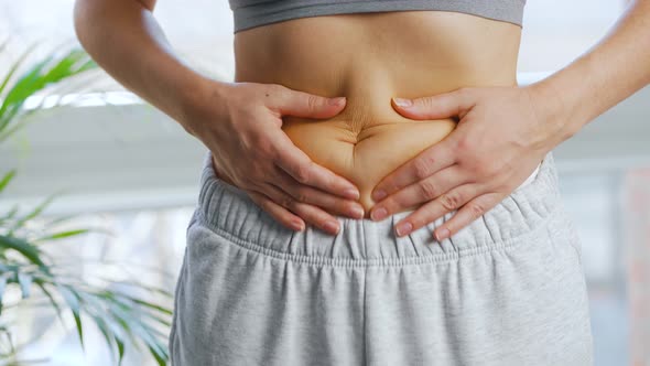 Woman Compressing the Skin on Her Stomach and Sides Checking for Excess Subcutaneous Fat